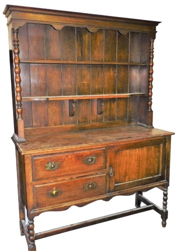 An oak dresser, with plate rack back, on twist column supports with two drawers and single cupboard, on H frame base with partial twist legs.