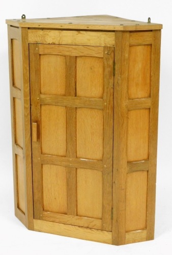 An oak Rabbit Crafts corner cabinet, with panelled oak design opening to reveal two shelves, 92cm high, 74cm wide, 48cm deep.