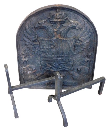 A 19thC cast iron fire back, decorated with a heraldic shield, 53cm x 44cm, and two fire dogs.