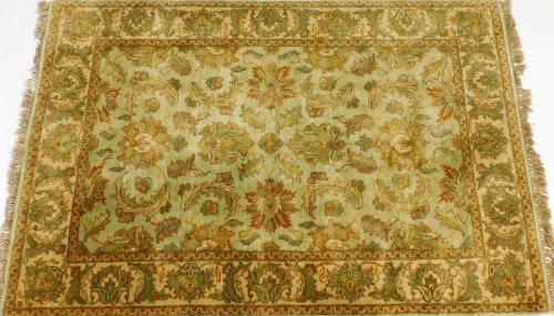 A Kashan pale green ground rug, decorated with floral and foliate motifs, within a repeating floral and foliate border, 163cm x 122cm.