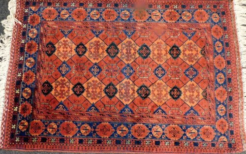 An Afghan red ground rug, decorated with floral medallions within a floral border, 160cm x 110cm.