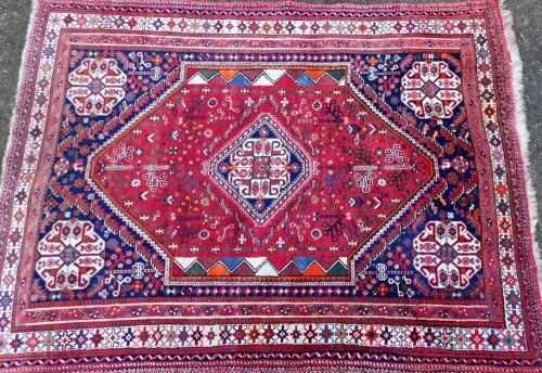 A Caucasian red and blue ground rug, the central medallion in a surround of flowers of dog tooth decoration, 195cm x 150cm.