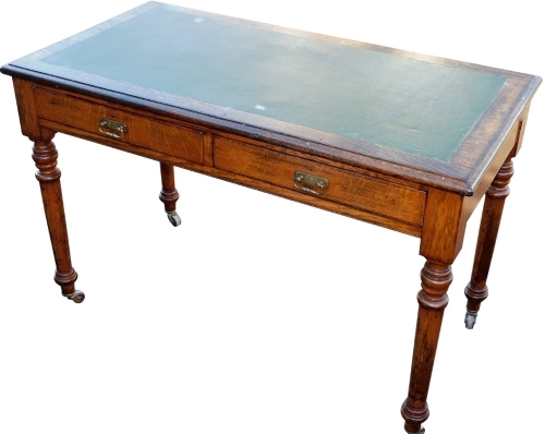 An early 20thC oak desk, the top with a green leather inset above two frieze drawers, on turned legs on castors, 114cm wide.