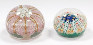 A Murano glass paperweight, decorated with daisies, pink latticino and gold ribbon strands, 9.5cm diameter, together with a concentric millefiori and latticino glass paperweight, against a green ground, 6.5cm diameter. (2) - 3