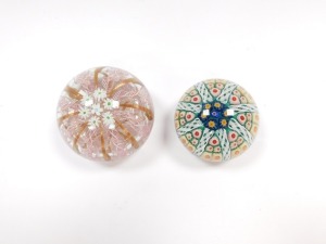 A Murano glass paperweight, decorated with daisies, pink latticino and gold ribbon strands, 9.5cm diameter, together with a concentric millefiori and latticino glass paperweight, against a green ground, 6.5cm diameter. (2) - 4