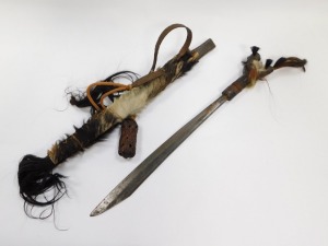A Borneo Dayak Mandau, with a carved wooden bi-form handle set with animal hair, copper and wire bound, the blade of curved, plain form, in a bamboo sheath with carved and bound detailing, set to the rear pouch with animal's hair, enclosing a Langgei Puai - 2