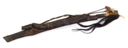 A Borneo Dayak Mandau, with a carved Aso head bone handle set with animal hair, metal and wire bound, the blade of curved, pierced and engraved form, in a wooden sheath with carved decoration and metal binding, set to the rear with a leather pouch, lackin