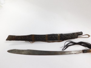A Borneo Dayak Mandau, with a carved Aso head bone handle set with animal hair, metal and wire bound, the blade of curved, pierced and engraved form, in a wooden sheath with carved decoration and metal binding, set to the rear with a leather pouch, lackin - 4