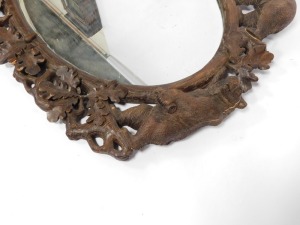 A 19thC wooden Black Forest oval wall mirror, the mirror plate in a carved frame of oak leaves, and four bears at intervals, 100cm high, 110cm wide. (AF) - 8