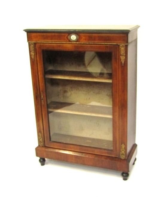A Victorian walnut pier cabinet, the ebonised edged top over a glazed door, enclosing two shelves, raised on a plinth base and turned ebonies feet, 107cm high, 76cm wide, 30cm deep.