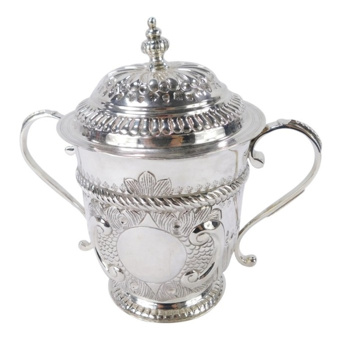 A George V Britannia silver copy of a seventeenth century porringer, of twin handled, covered form, with fluted and engraved decoration, oval vacant reserve, engraved No 131, Harry Freeman, London 1913, 12&frac12;oz, 17cm high.