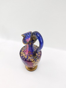 A late 19thC Bohemian pink and blue flashed glass ewer, decorated with shield reserves of deer and hunting dog, in a woodland setting, against a ground over decorated in gilt with trailing leaves, 33.5cm high. (AF) - 3