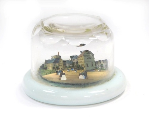 A 19thC faceted cut glass paperweight, decorated internally with a painted three dimensional scene of figures in a town, on opaline circular base, 9cm diameter.