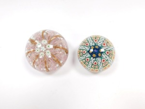 A Murano glass paperweight, decorated with daisies, pink latticino and gold ribbon strands, 9.5cm diameter, together with a concentric millefiori and latticino glass paperweight, against a green ground, 6.5cm diameter. (2) - 2
