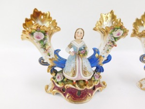 A pair of early 19thC Fischer & Mieg porcelain cornucopia vases, each encrusted with flowers and centred with a seated figure of a girl flower seller, raised on a naturalistic ground and rococo scroll base, one stamped CF324, the other F&M, 22cm wide. (AF - 2