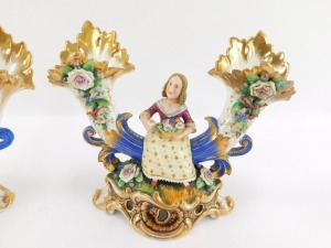 A pair of early 19thC Fischer & Mieg porcelain cornucopia vases, each encrusted with flowers and centred with a seated figure of a girl flower seller, raised on a naturalistic ground and rococo scroll base, one stamped CF324, the other F&M, 22cm wide. (AF - 3