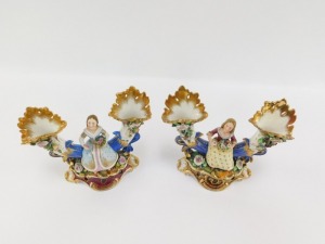 A pair of early 19thC Fischer & Mieg porcelain cornucopia vases, each encrusted with flowers and centred with a seated figure of a girl flower seller, raised on a naturalistic ground and rococo scroll base, one stamped CF324, the other F&M, 22cm wide. (AF - 5