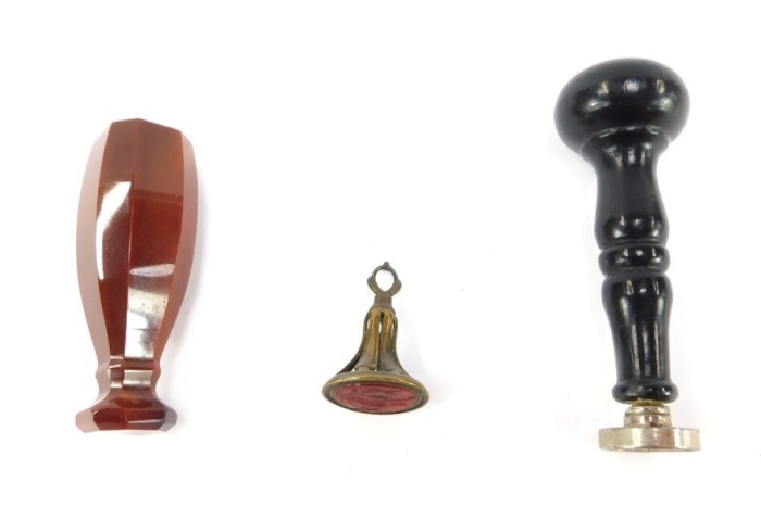 A Victorian agate seal, of canted rectangular form, undecorated, 6cm wide, and a late 19thC initialled seal, with a turned wooden handle, 1.5cm wide, and a gilt metal and carnelian intaglio crested seal of two hanging game birds. (3)
