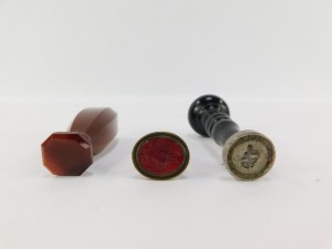 A Victorian agate seal, of canted rectangular form, undecorated, 6cm wide, and a late 19thC initialled seal, with a turned wooden handle, 1.5cm wide, and a gilt metal and carnelian intaglio crested seal of two hanging game birds. (3) - 2
