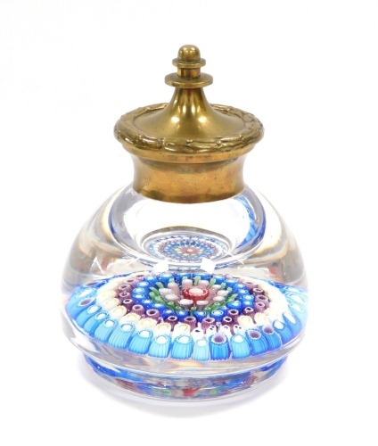 An early 20thC concentric millefiori glass ink well, possibly H G Richardson, with a brass mount and hinged lid, four marked canes within design, 11cm wide, 14.5cm high.