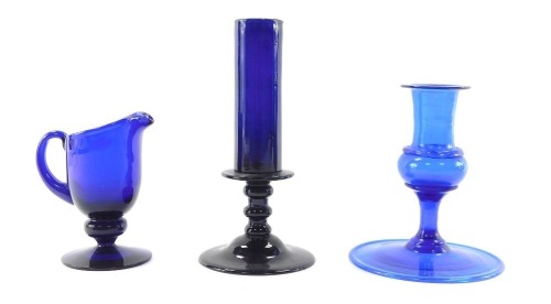 A 19thC Bristol blue glass candlestick, 17cm high, further blue glass candlestick on a broad circular base with inverted rim, 12.5cm high, and Bristol blue glass cream jug, 11cm high. (3)