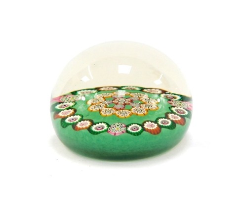 An early 20thC Paul Ysart millefiori paperweight, with a central millefiori flower, in a surround of green, red and pink millefiori canes, against a green ground, 8cm diameter.