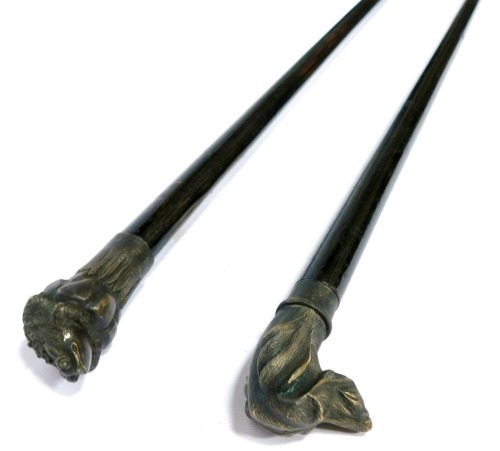 An ebonised walking stick, with a cast brass dog's head knop, 3cm wide, and a further walking stick, the knop cast as a frog atop a lily pad, 23cm wide. (2)