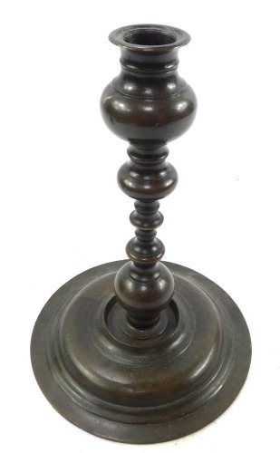 A 17thC style bronze candlestick, of baluster form, raised on a wide circular base, 21.5cm high.