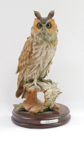 A Capo di monte figure of a long eared owl, on a circular mahogany base, signed G Armani, 35cm high.