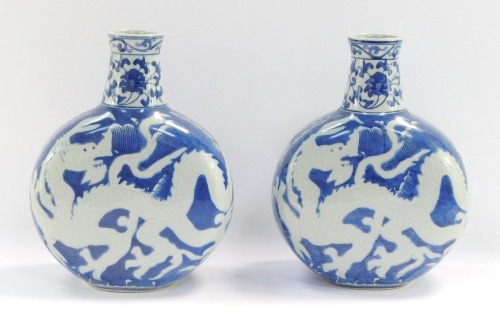 A pair of late 20thC Chinese blue and white moon flasks, each with a flared floral top, with dragon stem body, 25cm high.