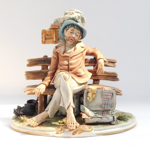 A Capo di Monte figure of a tramp on bench, painted mark and paper label, 21cm high.