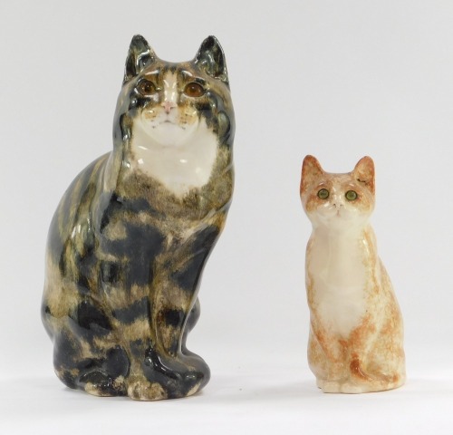 Two Winstanley pottery cats, comprising a black and brown tabby, with amber glass eyes, 31cm high, and a ginger perched cat, 20cm high. (2, AF)
