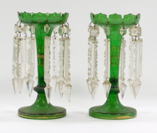 A pair of Victorian green glass lustres, each with gilt highlighted rim and stem, with eight prismatic drops, 24cm high.