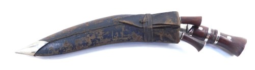 A Middle Eastern Kukri knife, the arched blade with a two part wooden handle, with two smaller sharpening knives, 43cm long.
