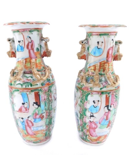 A pair of 19thC Cantonese porcelain famille rose vases, each with a flared rim, decorated with figures in a garden setting, with Dog of Fo gilt handles and dragon applied motifs, 25cm high.