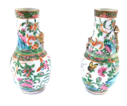 A pair of Cantonese porcelain famille rose vases, each with a gilt applied gilt dragon stem, on a bulbous body painted with flowers and butterflies, 15cm high.