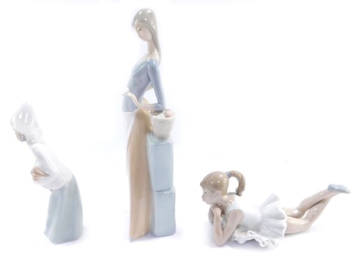 Three Nao and Lladro figures, comprising a Lladro figure of a child carrying a hen, 20cm high, a Nao figure of a seated ballerina, 10cm high, and a Nao figure of a lady with fruit basket, 30cm high.