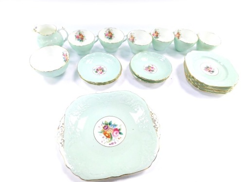 A Coalport porcelain part tea service, decorated with floral sprays against a moulded green ground, comprising bread plate, cream jug, sugar bowl, six cups, saucers, and tea plates.