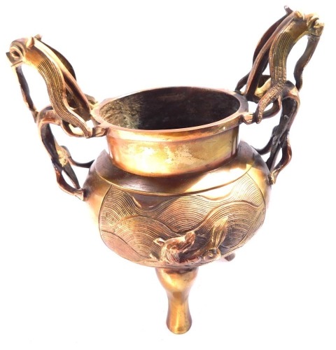 A Qing dynasty bronze censor, with dragon handles, the body decorated with reserves of dogs of Fo, on tripod feet, 18cm high.