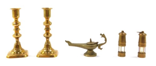 A small group of brass collectables, comprising a pair of candlesticks, 15cm high, a pair of miniature miner's lamps, 8cm high, and an Aladdin's oil lamp, 7cm high. (5)