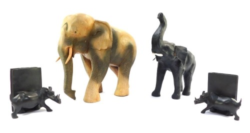 A group of carved wooden ornaments, comprising a large elephant 33cm high, a black stained elephant with replacement plastic tusks 33cm high, and a pair of warthog bookends 14cm high. (4)