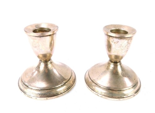 A pair of silver dwarf candlesticks, each with a ribbed top on a weighted base, stamped Sterling, 11&frac34;oz all in, 8cm high.
