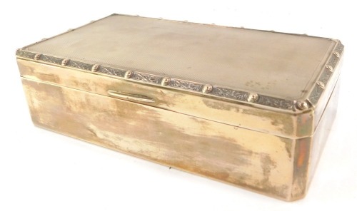 An Elizabeth II silver cigarette box, the Celtic banded top with engine turned decoration opening to reveal a wooden lined interior, Birmingham 1982, 16oz gross, 17cm wide.