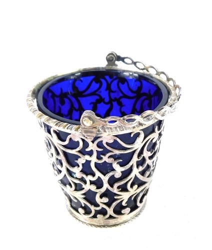 A George III silver sugar basket, with a Bristol blue glass liner, and swing handle, with pierced foliate decoration and vacant shield reserve, Thomas Shepherd, London 1777, 2oz