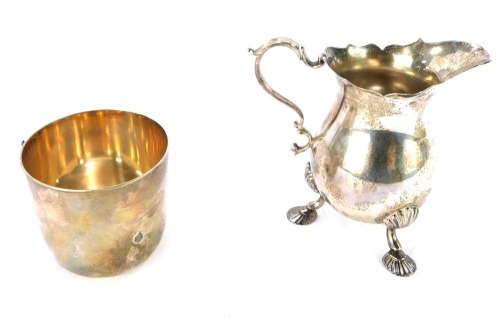 A Georgian style silver cream jug, of baluster form, with an s scroll handle, raised on three pad feet, London 1977, and a silver tot, of plain form, London 1968, 6&frac12;oz.