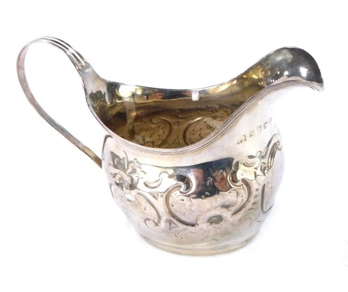A George III silver cream jug, of spiral fluted baluster form, embossed with trailing leaves, oval shield reserve crest engraved, raised on three trefoil feet, William Kersill, London 1768, 2&frac12;oz.
