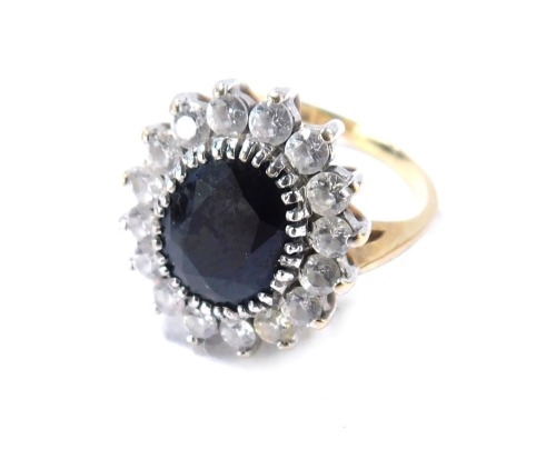 A 9ct gold cluster ring, set with imitation sapphire, surround by CZ stones, in raised basket setting with applied leaf design shoulders, size T, 3.2g all, boxed.