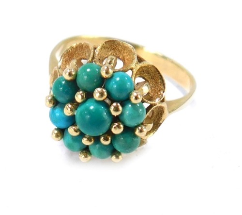 A turquoise dress ring, the turquoise cluster on fluted bark effect petal detail, on yellow metal band, unmarked, size O&frac12;, 4.2g all in.