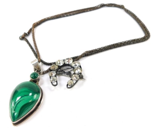 Two items of jewellery, comprising a malachite and silver tear drop pendant, 6cm high, on a plated chain, together with a white metal frame and paste stone set horseshoe brooch, 3cm high. (2)
