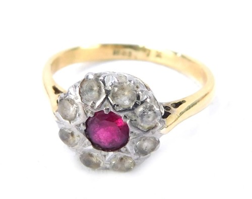 A ruby and diamond dress ring, the ruby surround by tiny diamonds in a platinum setting, with pierced design shoulders, yellow metal band stamped 18ct, size M, 3.3g all in.